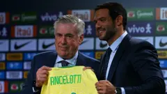 O novo técnico da seleção brasileira de futebol, o italiano Carlo Ancelotti (E), recebe a camisa do time das mãos do presidente da Confederação Brasileira de Futebol (CBF), Samir Xaud, durante sua apresentação oficial em um hotel na Barra da Tijuca, Rio de Janeiro, Brasil, em 26 de maio de 2025