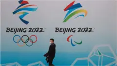 A man walks past a Beijing Olympics sign