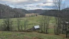 Celeiro em colina com árvores.