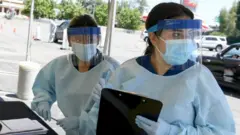 Health workers in PPE carry out coronavirus tests