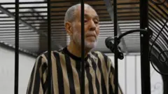 مُفتي سوريا السابق أحمد بدر الدين حسون يقف من وراء القضبان خلال محاكمته.
