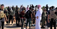 رجال يرتدي بعض منهم جلباب وأخرون سراويل سوداء وقمصان سوداء، وهم مدججون بالسلاح.
