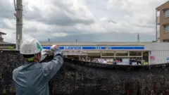 Trabalhador instala uma barreira para bloquear a vista do monte Fuji, no Japão, a fim de deter turistas mal comportados, na cidade de Fujikawaguchiko, no distrito de Yamanashi, em 21 de maio de 2024