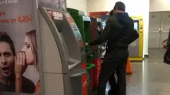 Банкоматдан пул чиқараётган мигрантлар