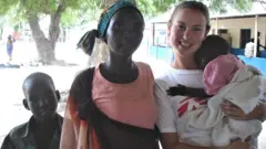Anna Kent with her patients and holding a child in her arms