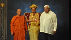 ශ්‍රී දළදා මාලිගාවේ 19 වන දියවඩන නිලමේ ප්‍රදීප් නිලංග දෑළ සිය මව (වම) සහ පියා (දකුණ) සමග. මව භික්ෂුණියක වන බැවින් මෙහි උන්වහන්සේ සිවුරක් ඇඳ සිටී.