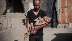 Malik, de 6 años, en brazos de su padre