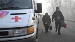 Поліцейський йде поруч з бабусею для евакуації в Гуляйполі