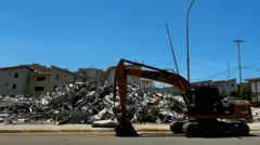Se ve una grúa frente a varios edificios bajo los escombros.