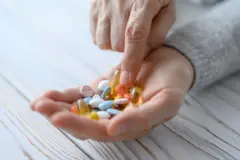 Una mujer mira diferentes tipos de pastillas que tiene en la mano