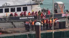 
እቶም ስደተኛታት ብሰንበት ብመርከብ ናይ ሓለዋ ዶብ ኣብ ወደብ ዶቨር እናወረዱ እንከለዉ ዘርኢ ስእሊ
