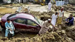 People struggle to retrieve a car from mud and debris after flash floods in the Buner district of the monsoon-hit northern Pakistani province of Khyber Pakhtunkhwa, on 16 August 2025.