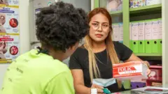 一名護士向助產士展示一盒用於產前和產後婦女服用的葉酸