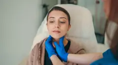 Mulher sentada passa por exame físico da tireoide