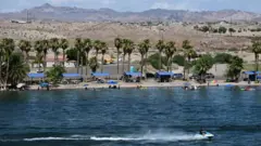 A person rides a jet ski as others picnic in the water at Davis Camp Park on the Colorado River in Bullhead City, Arizona on June 27, 2022