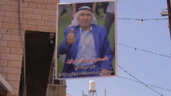 تصویر رنگی یک مرد با کت و شلوار و چفیه که به دیوار نصب شده است