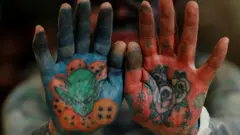 A man shows his tattooed palms to the camera