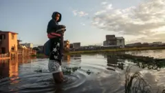 ህጻን ልጅ ሽኮኮ ብሎ በጎርፍ ውስጥ የሚራመድ ሰው