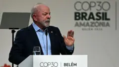 Lula gesticulando em palanque, com painel da COP30 atrás