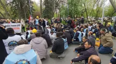 Ankara'da 22 Nisan'da bir parkta kalabalık bir madenci grubu yere oturuyor ve basın açıklamasını izliyor. 