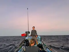 Dois dos irmãos no barco, com um lindo pôr do sol rosa ao fundo