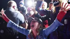 Una mujer con los brazos abiertos en celebración en acto de campaña de Trump en Mosinee.
