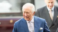 Король Чарльз у синьому костюмі і сірій краватці посміхається 