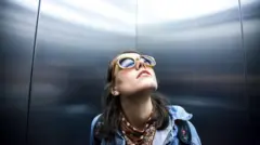 Mujer en un ascensor mirando hacia arriba