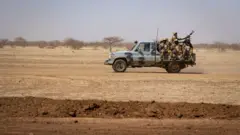 Des soldats burkinabés patrouillent à bord d'un pick-up sur la route de Dori au camp de réfugiés de Goudebo, le 3 février 2020.