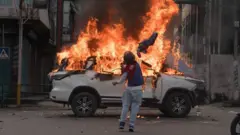 demonstrant baca kamen na zapaljen automobil