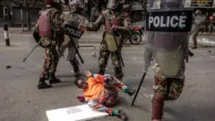 Umwe mu bari mu myiyerekano ariyama aryamye hasi, abapolisi bari hejuru yiwe
