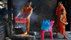 Três jovens monges preparam comida no fogo