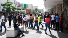 建物の外や路上に大勢がいる。中には蛍光黄色のヘルメットとベストを着けた人もいる