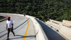 Di bus crash through one barrier on di bend in di road