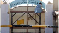 Des talibans remplacent une plaque du département des affaires féminines par le ministère de la promotion de la vertu et de la prévention de la toxicomanie à Kandahar, en Afghanistan, le 20 octobre 2021.