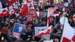 Pessoas carregando bandeiras da Groenlândia e cartazes com os dizeres 'A Groenlândia não está à venda' marcham na capital groenlandesa, Nuuk, em protesto contra o presidente americano Donald Trump e sua anunciada intenção de adquirir a ilha, no dia 17 de janeiro de 2026.