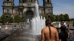 Pessoas se refrescam na fonte em frente à Catedral de Berlim durante a atual onda de calor