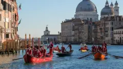 مجموعة من المتسابقين يرتدون زي سانتا كلوز يشاركون في سباق قوارب في فينيسيا بإيطاليا