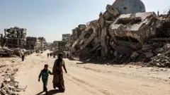 Uma mulher e uma criança caminhando de mãos dadas entre edifícios destruídos por ataques israelenses em Beit Lahia, uma cidade no norte da Faixa de Gaza, em 18 de fevereiro de 2025 (Foto: Abd Khaled/Anadolu via Getty Images)