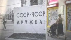 زنی با کالسکه در حال عبور از مقابل بیلبوردی به مناسبت سی امین سالگرد خروج نیروهای شوروی از پراگ پایتخت جمهوری چک