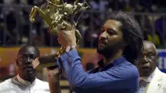 Le lauréat du 25e Festival panafricain du cinéma et de la télévision (FESPACO) Alain Gomis brandit le trophée de l'étalon de Yennega au Palais des sports de Ouagadougou, le 4 mars 2017.