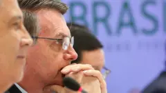 Bolsonaro de perfil, ao lado de dois ministros, em reunião