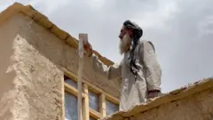 सिग्नल राम्रो नभएको ठाउँमा प्लास्टिकको रित्तो भाँडामा फोन राख्दै एक अफगान वृद्ध