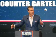 Hegseth gesticulando ao discursar em frente a painel que diz 'combate aos cartéis'