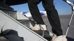 One Honduran immigration detainee, wey dem bind im legs and shoes lace as security precaution, dey board one deportation flight go Honduras