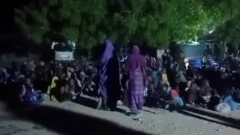 Two women wear purple wit oda children siddown for floor.