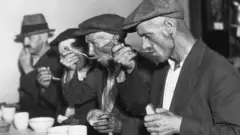 Homens tomando sopa com pão durante a Grande Depressão nos Estados Unidos