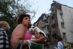 Moradora de cidade bombardeada na Ucrânia na rua segurando um gato