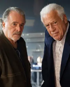 Dois homens idosos encaram a câmera com expressão séria. O da esquerda, Tony Ramos, usa uma camiseta escura com um casaco marrom por cima, e óculos pendurados na gola; o da direita, Antonio Fagundes, veste camisa xadrez clara sob um blazer azul.