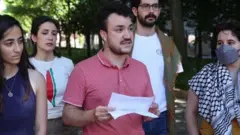 Mahmoud Khalil, rodeado por cuatro amigos, sujeta un papel en la mano. 